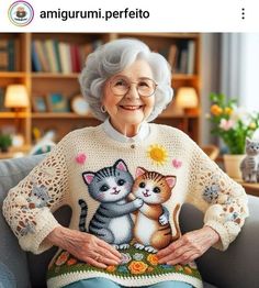 an older woman sitting on top of a couch next to a cat and kitten sweater