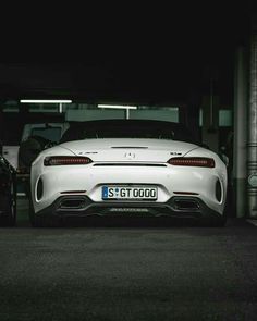 the rear end of a white sports car parked in a parking garage