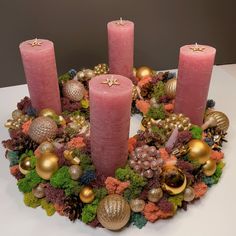 three pink candles sitting on top of a wreath