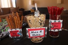 a table topped with lots of snacks and candy bar wrapper containers filled with nuts and toffes