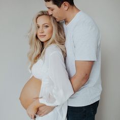 a man and woman standing next to each other in front of a white wall with the caption's name on it