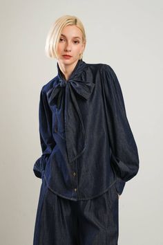 A chambray top featuring front bow tie, button down and long blouson sleeve. Matching pant FP1350 Details: Self : 100% Cotton Size & Fit - Model is 5`8" And Wearing Size Small- Measurements Taken From Size Small- Approx. Length: 24" Blouson Sleeve, Chambray Top, Suede Coat, Skirt Jumpsuit, Bow Blouse, Dark Indigo, Vintage Inspired Design, Swimsuit Cover, Sweatshirt Dress