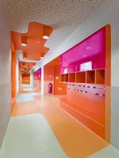 an orange and pink hallway with lockers on the wall, lights in the ceiling