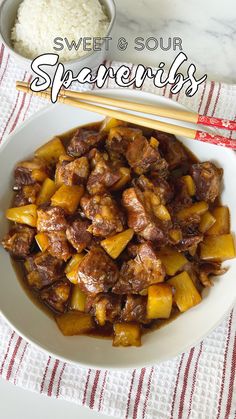 a white bowl filled with meat and pineapples next to chopsticks on a table