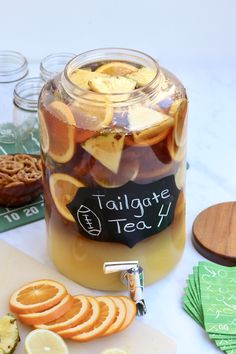 a jar filled with sliced oranges next to some pretzels and crackers