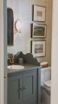 a bathroom with a sink, toilet and pictures on the wall above it's door