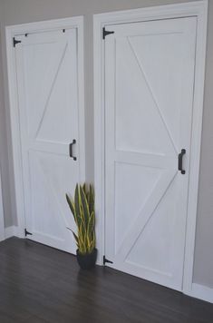 two white doors with plants in them on a wooden floor next to the door and wall