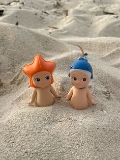 two small toy figures sitting in the sand