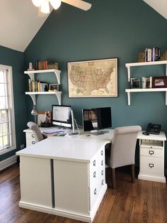 a home office with two computer desks and bookshelves on the wall above them