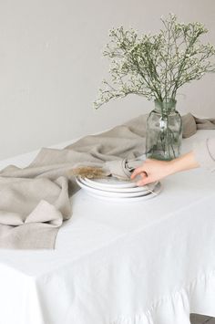 a white table topped with plates and vase filled with flowers