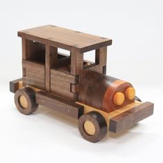 a wooden toy truck with logs on the front and back wheels, is shown against a white background