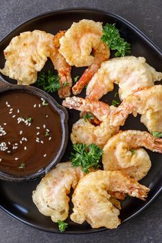 shrimp with dipping sauce on a black plate