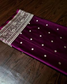 a purple and white sari laying on top of a wooden floor