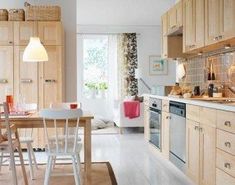 an open kitchen and dining area with wooden cabinets, white flooring and beige walls