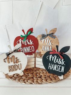 three wooden apples with names on them sitting in a basket next to some other decorations