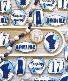 cookies decorated with blue and white frosting are arranged on a wooden tray, along with other cookie decorations