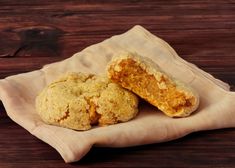 two cookies sitting on top of a piece of parchment paper next to a wooden table