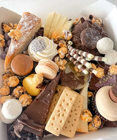 a white box filled with lots of different types of desserts and pastries on top of each other