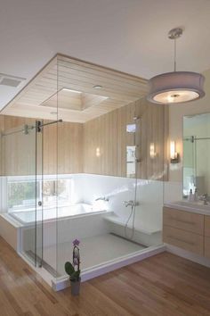 a large bathroom with wooden floors and walls, along with a glass enclosed bathtub