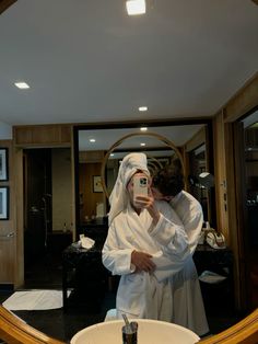 a man taking a selfie in front of a mirror wearing a robe and holding a camera