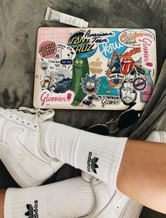 a person's legs with white socks and some stickers on their feet next to a purse