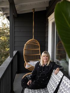 a woman sitting on top of a porch next to a hanging chair