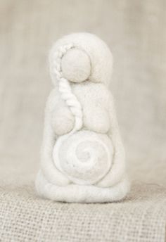 a white figurine sitting on top of a cloth covered couch next to a wall