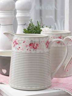 two white pitchers sitting on top of a table