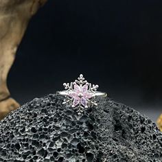 a snowflake ring sitting on top of a rock in front of some rocks