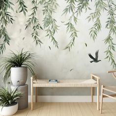 two chairs and a bench in front of a wall with green leaves painted on it