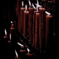 many red candles are lit in the dark