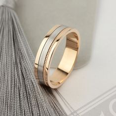 two tone gold and silver wedding band ring on top of a tasseled book