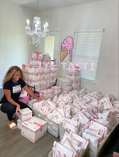 a woman kneeling on the floor in front of stacks of pizza boxes with one hand up to her head