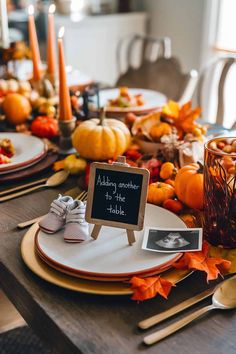 a table set for thanksgiving with pumpkins, candles and other autumn decorations on it