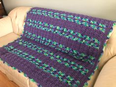 a purple crocheted blanket sitting on top of a couch