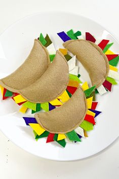 two pieces of felt sit on top of a white plate with multicolored paper