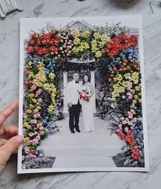 a man and woman standing in front of a floral arch