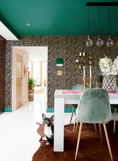 a dog sitting in the middle of a room with a table and chairs next to it