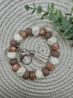 a bracelet with several different colored beads and a tassel on top of it next to a potted plant