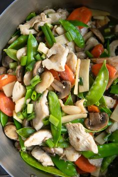 a pan filled with vegetables and meat on top of a stove