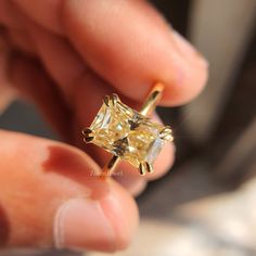 a person holding a yellow diamond ring in their hand