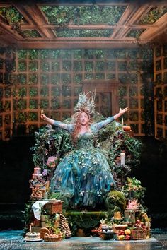 a woman dressed as a fairy sitting on top of a chair with her arms outstretched