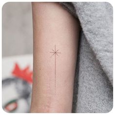 a person's arm with a small cross tattoo on the left side of their arm