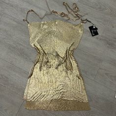 a gold dress on the floor next to a cell phone