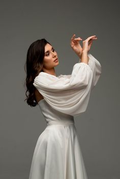 a woman in a white dress is posing for the camera