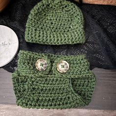 a green crocheted hat with two buttons on it and a pair of eyes