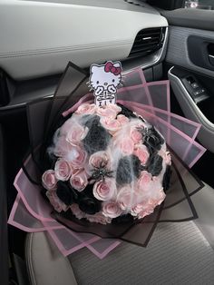 a hello kitty birthday cake sitting on top of a car seat with pink roses in the center