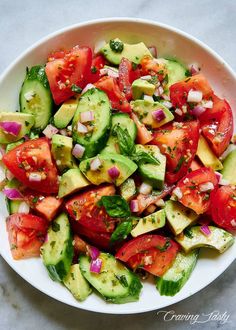 a white bowl filled with cucumber and tomato salad