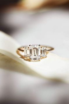 three stone ring sitting on top of a white flower