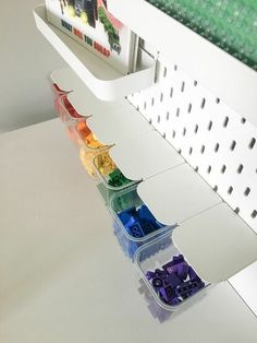 a row of plastic containers sitting on top of a white table next to a shelf